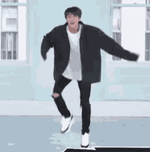 a man in a black jacket is dancing on a dance floor in a room .