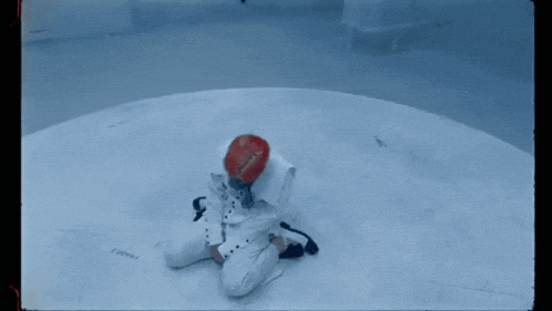 a person wearing a red hat and a white jacket is kneeling down