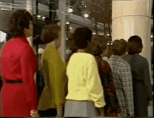 a group of women are standing in a line in front of a glass door