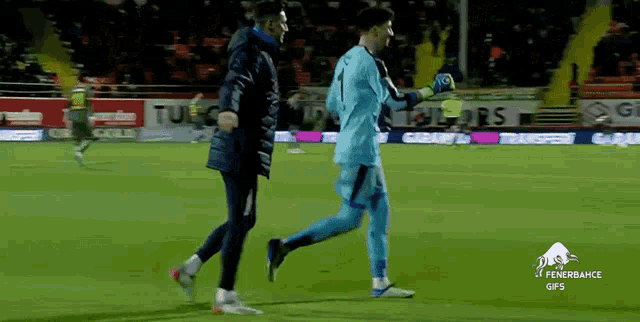 two soccer players are walking on a field with a banner that says tudor on it
