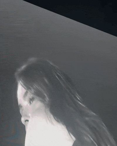 a close up of a woman 's face with long hair in a dark room
