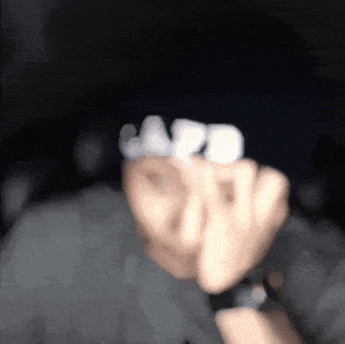 a person wearing a black hat and a watch holds a marshmallow in their fist
