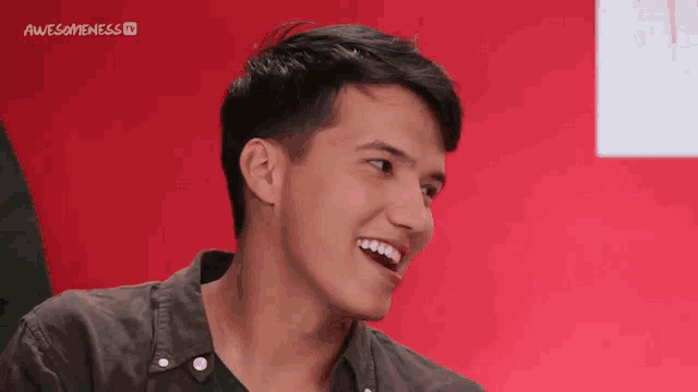 a young man is smiling in front of a red background with awesomeness tv written on it