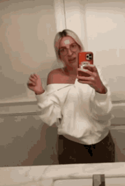 a woman is taking a selfie in the bathroom mirror .