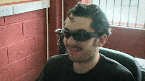 a man wearing sunglasses and a black shirt smiles for the camera