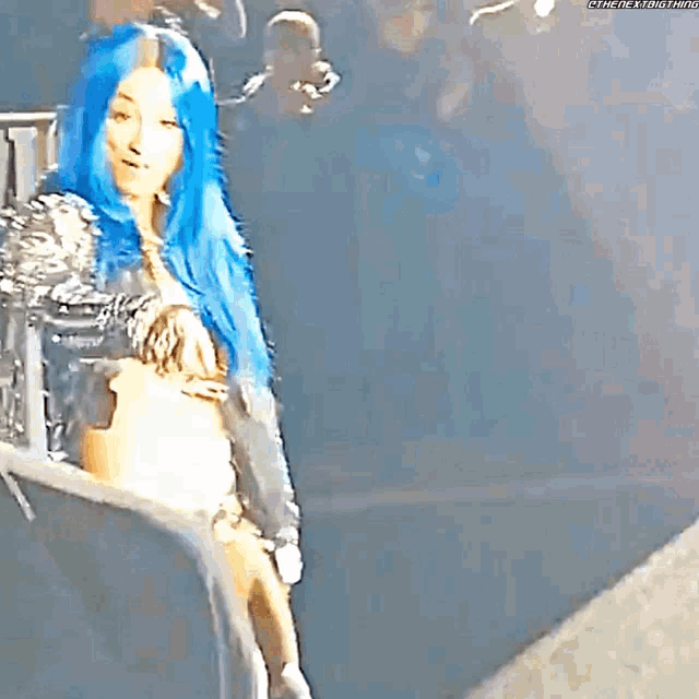 a woman with blue hair is standing on a stage .