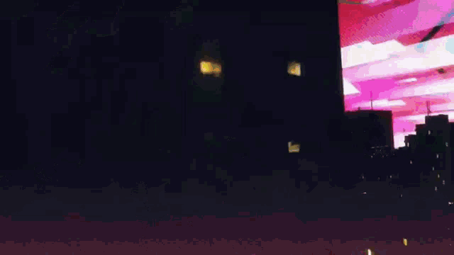 a computer generated image of a city at night with a large screen in the foreground .