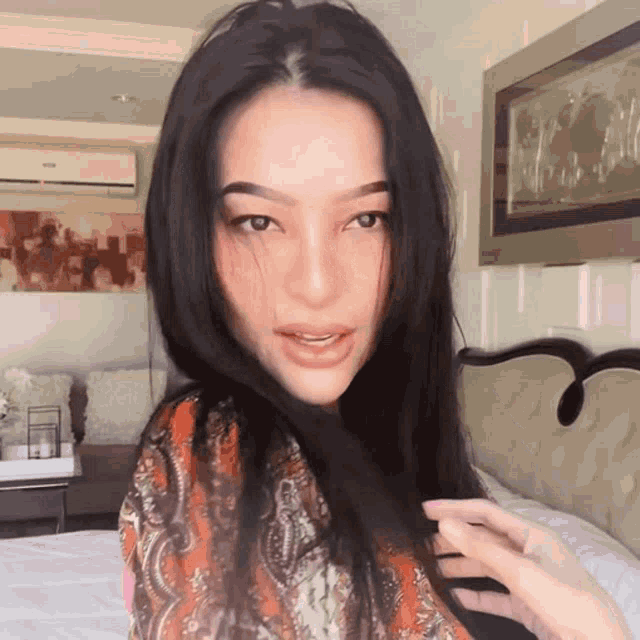 a woman with long hair is standing in a bedroom