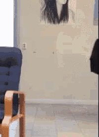 a person is standing in front of a chair with a picture of a woman on the wall behind them