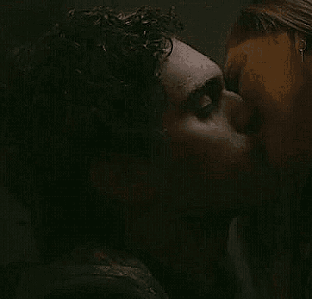 a man and a woman are kissing in the dark in a dark room .