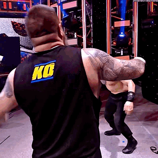 a man wearing a black tank top with a ko logo on the back
