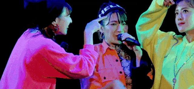 a woman singing into a microphone while two other women watch
