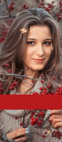 a woman in a grey sweater is holding a branch with red berries