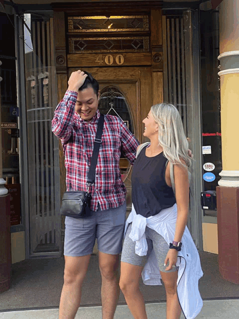a man and woman standing in front of a building with the number 400 on the door