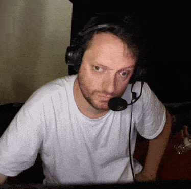 a man wearing headphones and a microphone is looking at a monitor