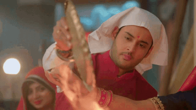a man wearing a white turban holds a candle in his hand