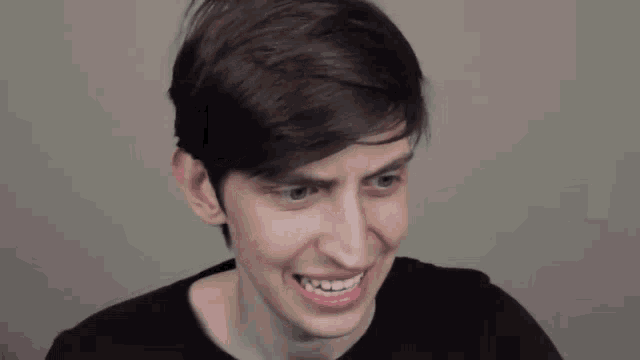 a young man in a black shirt is smiling and making a funny face