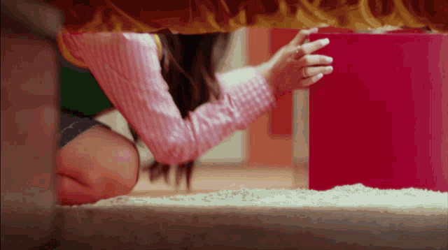 a girl in a pink shirt is reaching for something