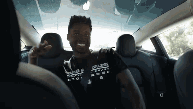 a man sitting in the back seat of a car wearing a t-shirt that says club82