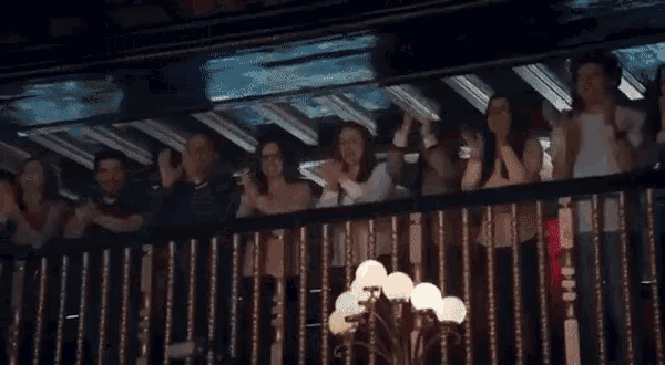 a group of people are standing on a balcony watching a show .