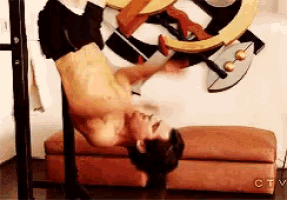 a shirtless man is doing a handstand in front of a painting on a wall .