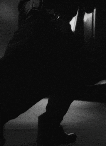 a woman in a black suit is standing in the rain