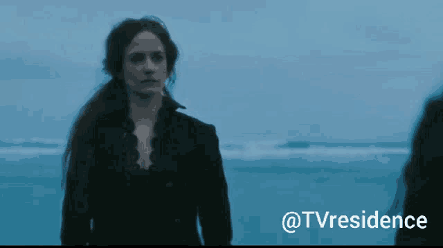 a woman standing on a beach with the words @tvresidence behind her