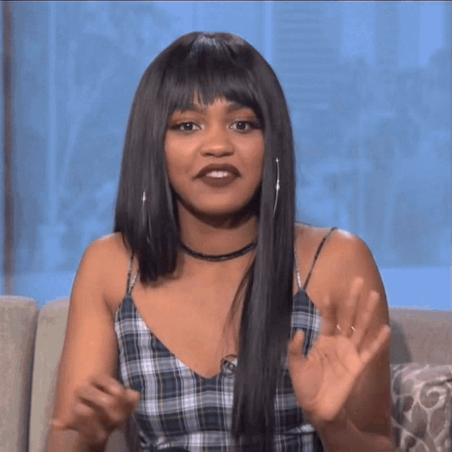 a woman sitting on a couch with her hands up