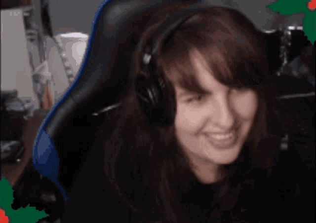 a woman wearing headphones is smiling and sitting in a gaming chair
