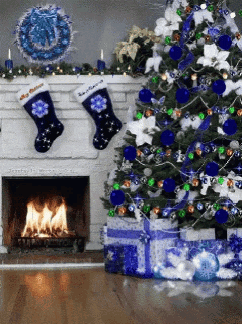 a christmas tree with blue and green decorations and a fireplace with two stockings hanging from it