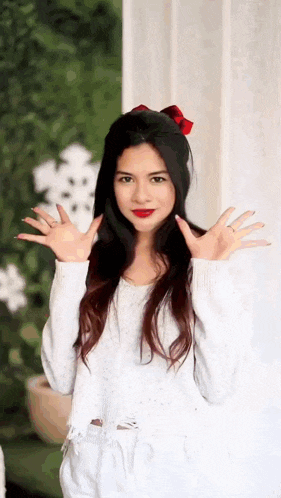 a young woman wearing a white sweater and red lipstick is making a funny face .