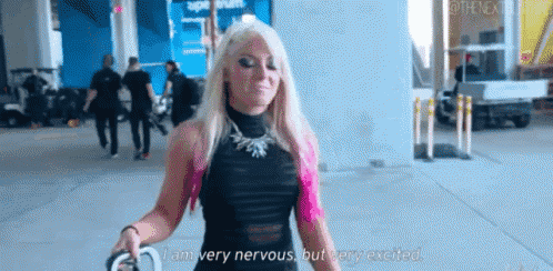 a woman with blonde hair and pink highlights is walking down a sidewalk holding a leash .