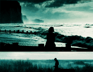 a silhouette of a person walking on a beach with waves crashing on the shore