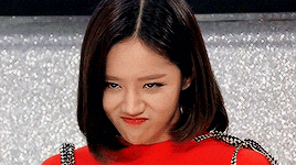 a woman with short hair is making a funny face while wearing a red sweater .