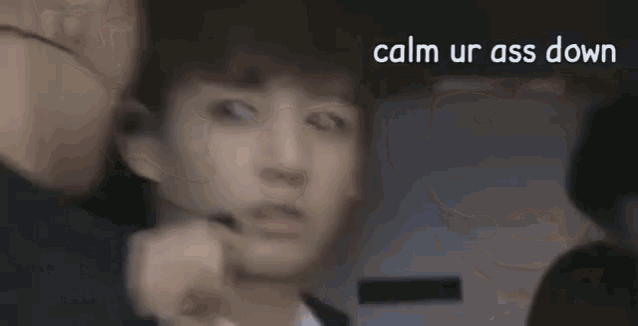 a close up of a person 's face with the words `` calm ur ass down '' written in the corner .