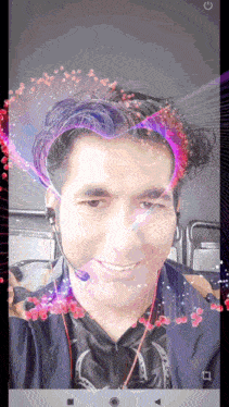a man wearing headphones and a headset looks at the camera with a glowing heart in his hair