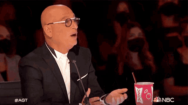 a bald man in a tuxedo is clapping in front of a sonic drink