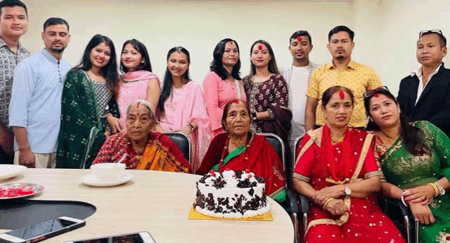 a group of people posing for a picture with a cake in the middle