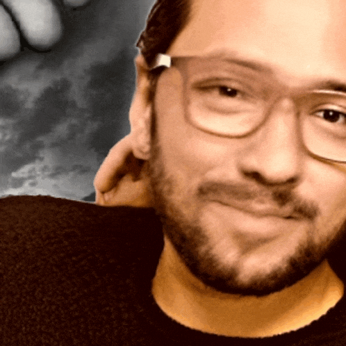 a man with glasses and a beard is smiling