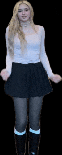 a woman wearing a white top and a black skirt is standing in front of a black background .
