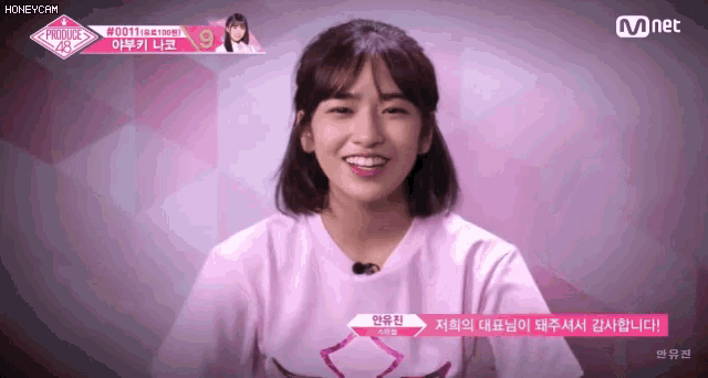 a girl in a pink shirt is smiling in front of a pink background .