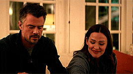 a man and a woman are sitting on a couch and smiling .