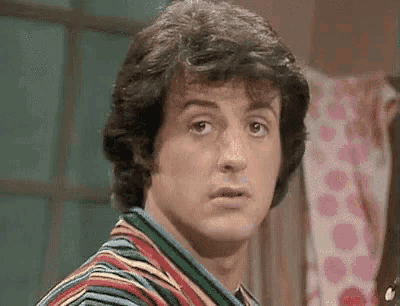a man in a striped shirt is making a funny face and looking at the camera .