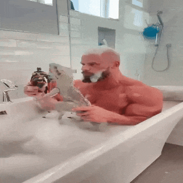 a shirtless man is taking a bath in a tub