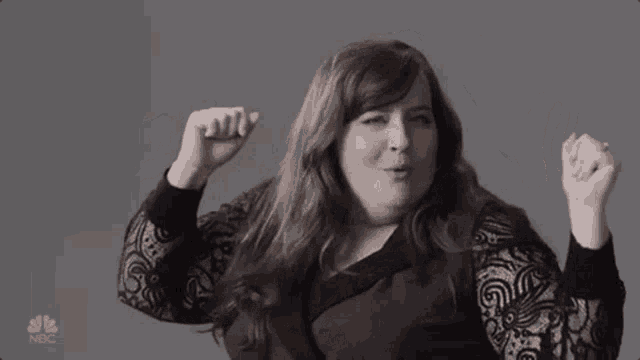 a woman in a black sweater is dancing with her hands in the air .