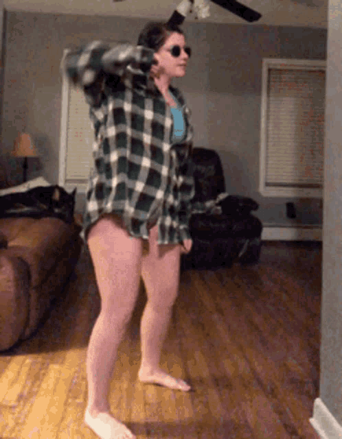 a woman in a plaid shirt and shorts is standing in a living room
