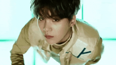 a close up of a young man wearing a jacket and a turtleneck is looking at the camera .