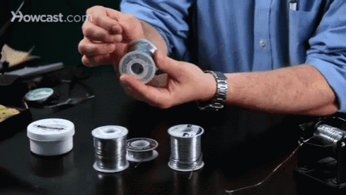 a man is holding a spool of solder in front of a howcast.com advertisement