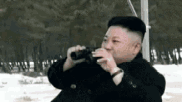 a man in a black suit is looking through binoculars .