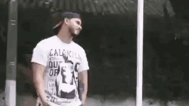 a man wearing a white shirt and a hat is standing in front of a window .